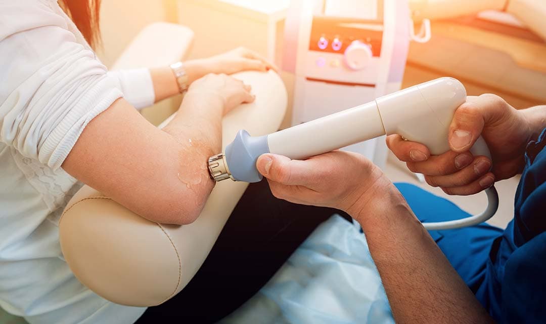 Laser machine pointed at the elbow of a patient