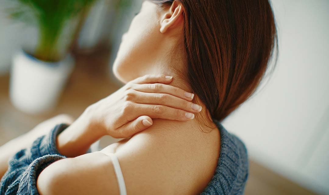 View of from the back of a woman with head tilted and hands on her neck