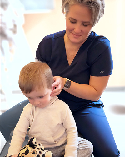 Dr Christy Flitwick sitting behind a young child, massaging their neck.